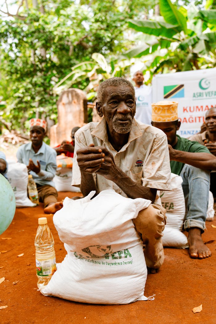 An elderly man with a food package during a distribution event in a rural setting.